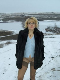 Зрелая женщина позирует голой в поле на снегу